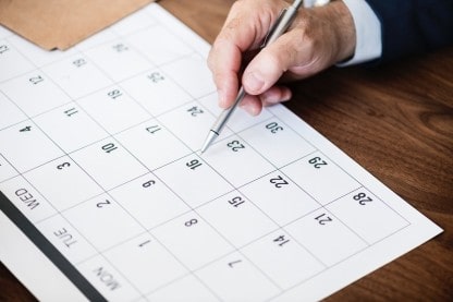 Photo of a pen poised over a calendar